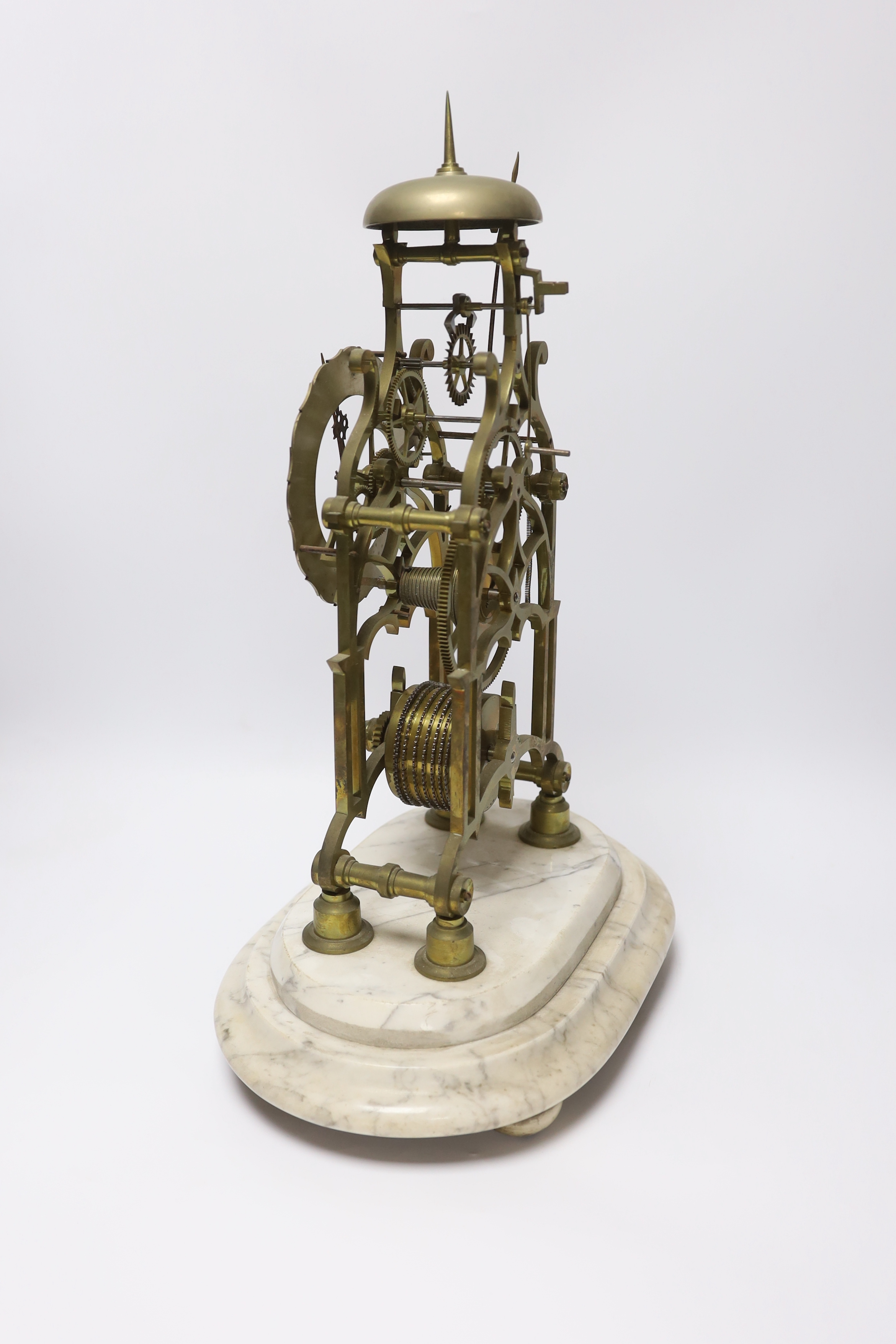 A skeleton clock with Roman numeral dial, raised on white marble base, pendulum and key, 45cm
